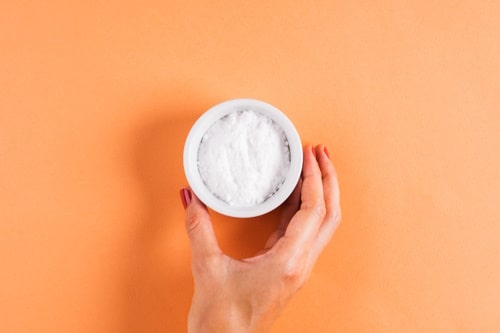 Baking soda in bowl on orange background