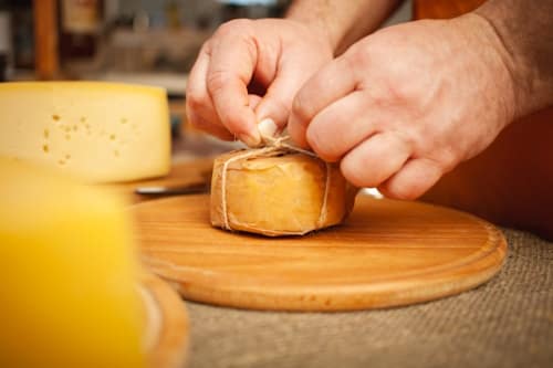 Person preparing small block of cheese