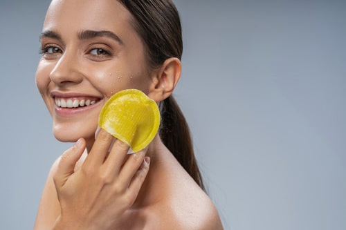 Woman using yellow scrubber on her face