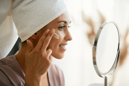 Beautiful woman applying face cream 