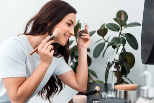 Woman putting on make up while using a mirror