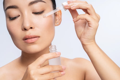 Woman pouring salicylic acid on her face with dropper