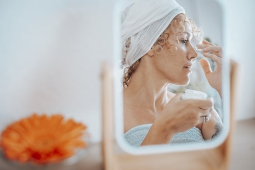 Woman applying cream on nose 