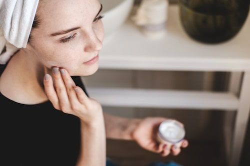 Young woman applying face cream