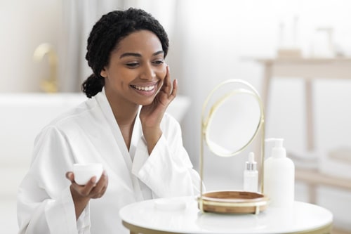 Beauty rituals attractive black woman applying moisturizer 