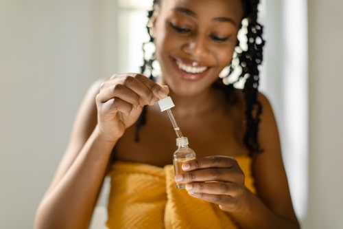 Black lady holding open bottle with hydrogen peroxide