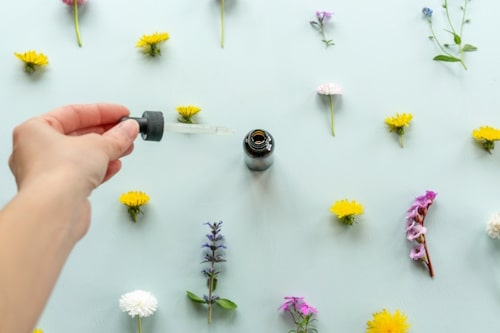 Hand holding dropper with flowers as background