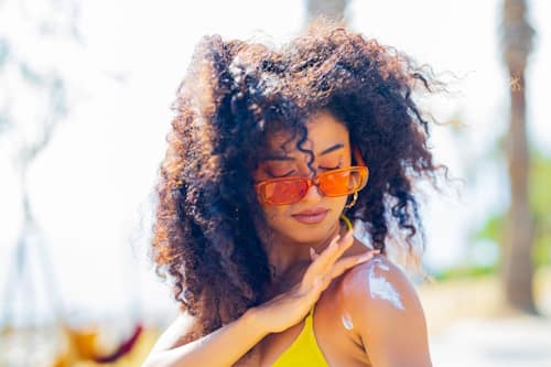 Curly haired woman putting on sun screen