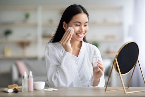 Asian woman applying skin care products to her face