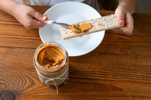 Natural peanut butter being used on crackers