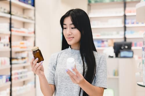 Young woman choosing multivitamin in pharmacy