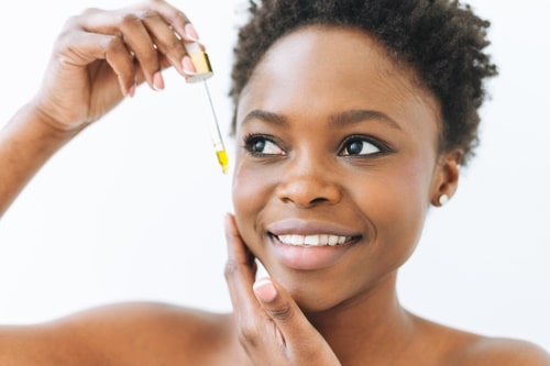 Close up beauty portrait of african woman with tea tree oil 