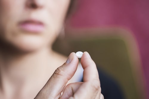 Closeup of woman looking at antibiotic tablet