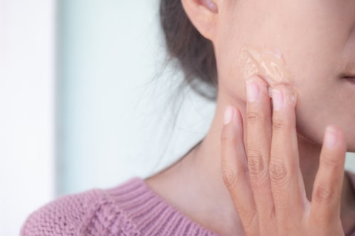 Woman applying aloe vera on her face