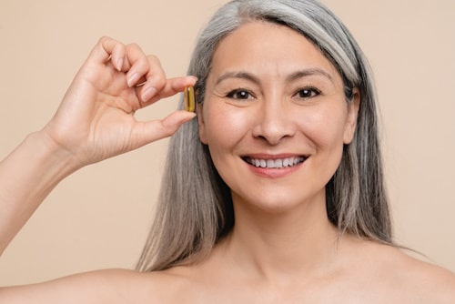 Closeup cropped mature middle aged caucasian holding collagen capsule