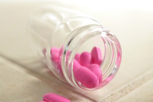 Tablets of benadryl inside a clear bottle tipped over
