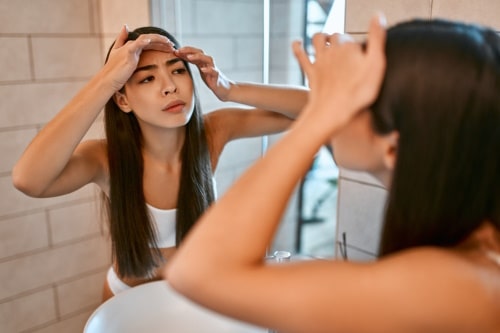 Woman trying to pop her acne on temples