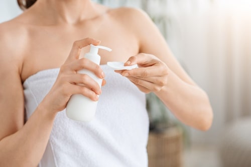 Woman pumping face toner to cotton pad