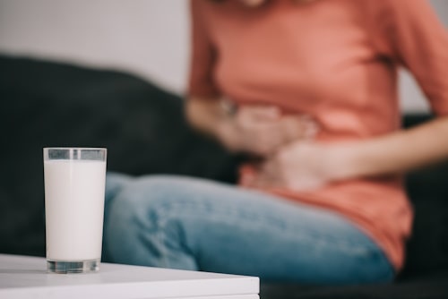 Image of glass of milk with lactose intolerant person in the background