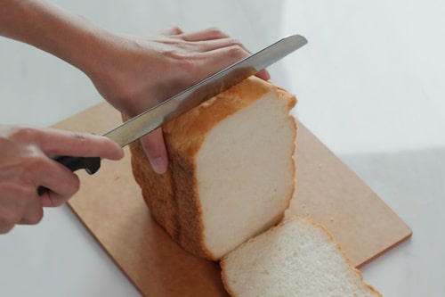 Person cutting white bread