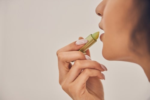 Image of woman using jojoba oil lip balm