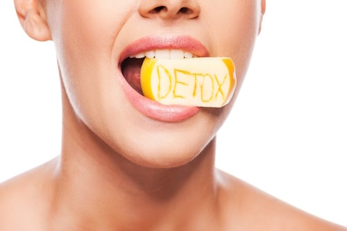 Woman biting lemon with the word detox written on it