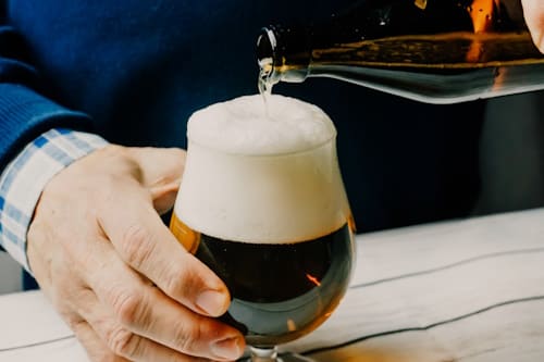 Person pouring beer into glass