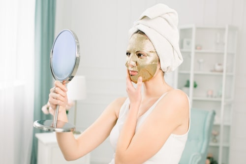 Woman looking at mirror with cucumber mask