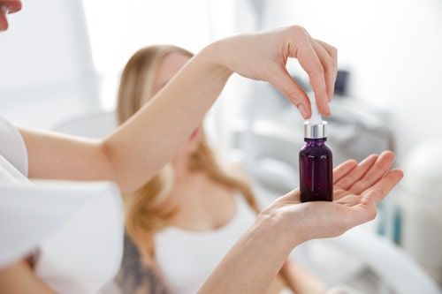 Female beautician hands holding bottle of vitamin a retinol