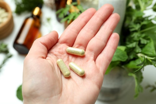 Female hand holds herbal medicine pills close up