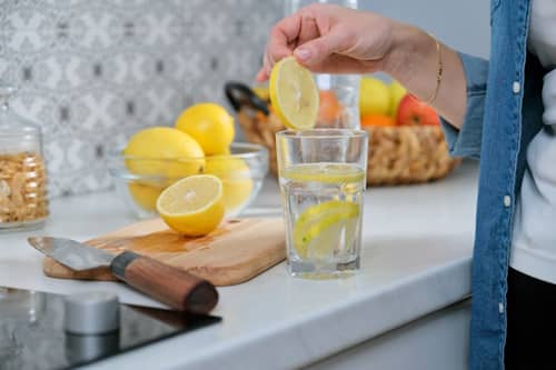 Person preparing lemon water in kitchen
