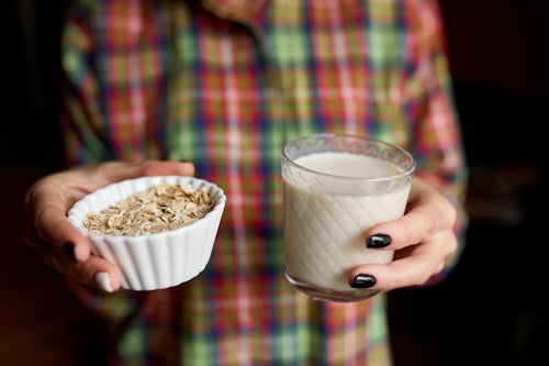 Person holding a class of oats and oat milk