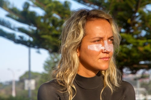 Girl surfer with zinc on face applying sunscreen 