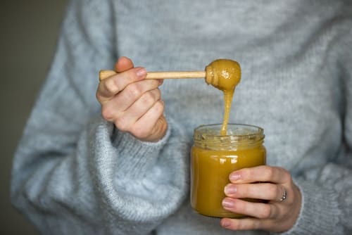 Young person holding jar of manuka honey