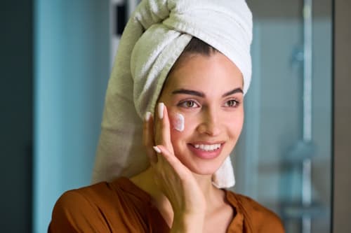 Newly showered woman moisturizing her face