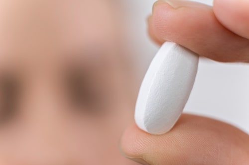 Macro photo of hand holding white pill medical 
