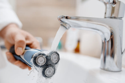 Man cleans electric razor after shaving 