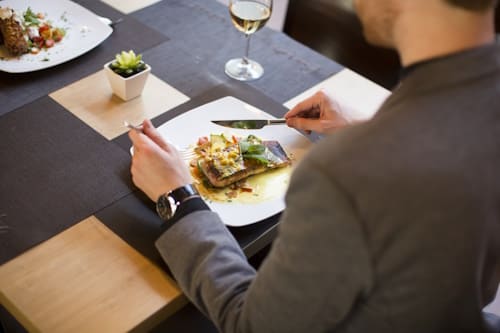 Back image of man eating salmon dish