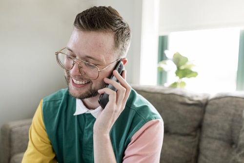 Man on phone call sitting on a couch at home