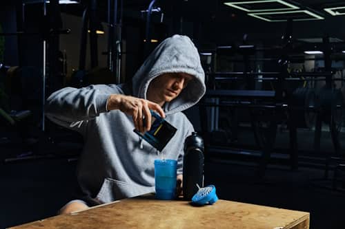 Young man wearing hoody mixing creatine and water
