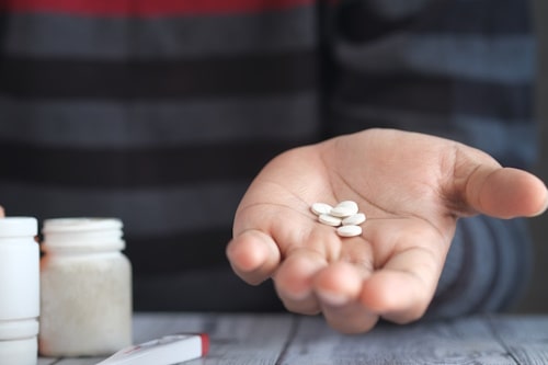 A hand holding antibiotic tablets