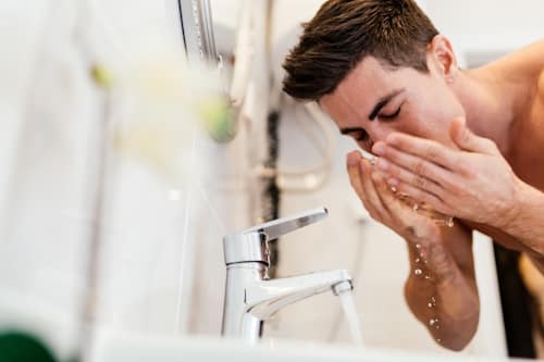 Young man washing his face