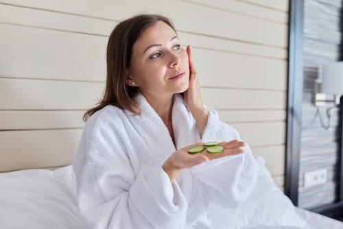 Woman applying cucumber juice on face