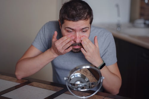 Man checking face skin with mirror