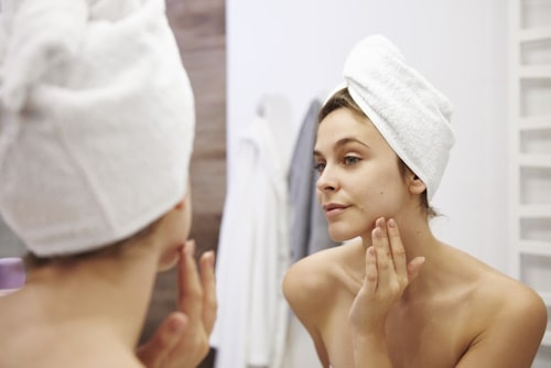 Mirror image of young woman examining her face