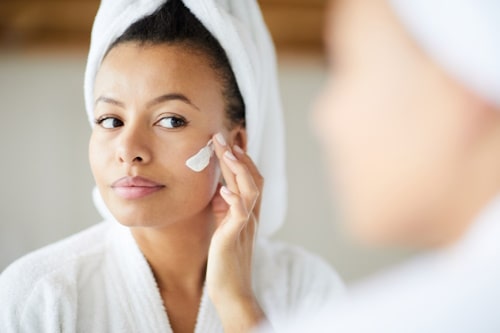 Woman applying vitamin a cream on her face