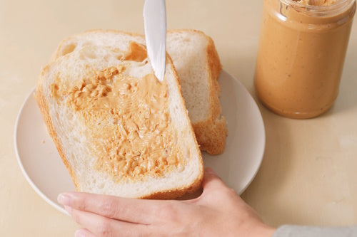 Peanut butter being spread on bread