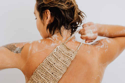 Woman overly scrubbing her back while showering