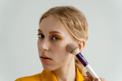 A woman using a make up brush on her face