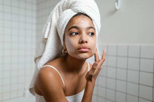 A woman moisturizing her face after taking a shower